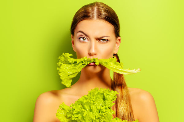 Vegan woman with piece of lettuce in her mouth 